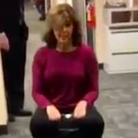 <p>News 12 anchor Colleen McVey riding a suitcase through the newsroom.</p>