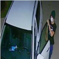 <p>The unidentified thief caught breaking into a car on surveillance footage</p>