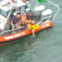 <p>Members of the Wading River Fire Department help the woman get out of the water and onto their boat.</p>