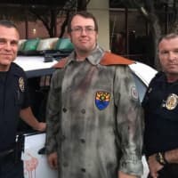 <p>Bryan Miller dressed as the self-described &quot;Arizona Zombie Hunter&quot; by his decommissioned police car covered in fake blood, alongside two Phoenix police officers.</p>