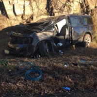 <p>A black SUV rests against a rock wall after crashing on Route 8 on Friday morning in Shelton. Three people inside had to be extricated by emergency crews. The morning commute was a tough one as traffic was backed up for miles.</p>