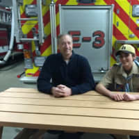 <p>Casey Meskers and Michael Waugh sitting at one of the picnic tables that Waugh built.</p>