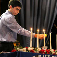 <p>WHS senior Steven Brunetto lighting candles during the National Honor Society induction ceremony.</p>