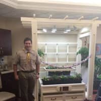 <p>Steven Orientale posing next to the indoor garden he built for the residents at Atria Briarcliff.</p>