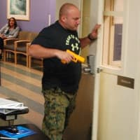 <p>Playing the part of the shooter, Ridgewood Police Sgt. Jay Chuck approaches an unsuspecting receptionist at The Valley Hospital</p>