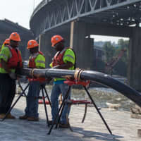 <p>Construction workers assemble conduits for the new Tappan Zee Bridge&#x27;s electrical system while standing on a temporary platform.</p>