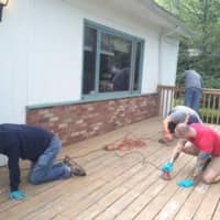 <p>Volunteers from Ryan Ryan DeLuca sand a deck.</p>