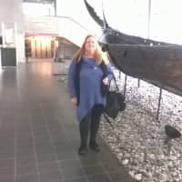 <p>Lydia Higginson stands next to Viking ship at a Viking museum.</p>