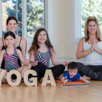 <p>Danielle holds 5 year old Luca, left, with Sienna, 9 to her right. Connor plays on the yoga mat next to Shari Germershausen.</p>