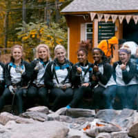 <p>The University of Bridgeport&#x27;s Women&#x27;s Gymnastics Team enjoys a moment around the fire pit after their October climb at The Adventure Park at The Discovery Museum.</p>