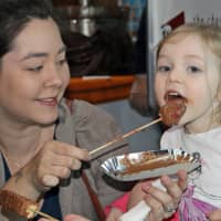 <p>A young visitor takes a big bite of chocolate at the expo on Sunday at the Maritime Aquarium at Norwalk.</p>
