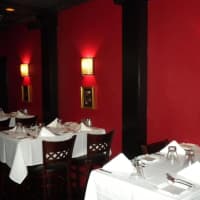 <p>Red walls and sconces provide a warm backdrop to white linen-clad tables in the dining room at Michael Gennaro&#x27;s Steakhouse.</p>
