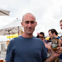 <p>Tim Cerniglia Jr. with a jar of his Greenwich-produced BeeKind Farms honey.</p>