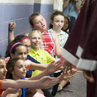 <p>Elementary school students in Bethel extend hands to connect with high school seniors as they paraded through the halls on Thursday.</p>