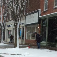 <p>Two guys with shovels clear the wide walkways on Main Street in Danbury on Friday.</p>