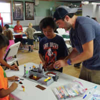<p>Pastor Dan Haugh from Round Hill Community Church in Greenwich helps a boy with a Lego project at a reservation in South Dakota.</p>