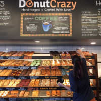 <p>Nicole Smith reaches for a customer favorite at Donut Crazy in Shelton. </p>