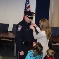 <p>Maryann Frengs, the wife of Brookfield Police Department Pete Frengs, pins on his Captain&#x27;s badge as their children watch at the ceremony.</p>