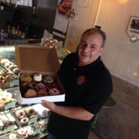 <p>Jule Hazou displays his freshly-made doughnuts in the New Milford store.</p>