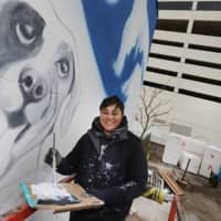 <p>Muralist Heather Hires paints the west side of Good Dog Bar AC with a brightly colored dog-themed mural.</p>