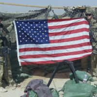 <p>Major Chris Carbone, left, holds the flag in Afghanistan on the 10th anniversary of 9/11.</p>