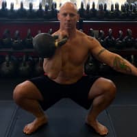 <p>American Eagle MMA owner Phil Ross of Mahwah does a kettle bell squat.</p>