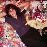 <p>Social media manager Lisa Karpowich of Emerson Dental Arts reclines on the small mountain of candy local kids brought in for the program.</p>