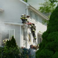 <p>Norwalk firefighters climb to the roof of a side entranceway at 43 East Ave. on Tuesday during a fire at the home.</p>