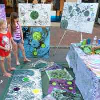 <p>Youths watch as an artist creates one of his works during Thursday night&#x27;s Art About Town street party.</p>