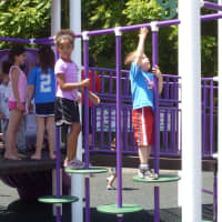 <p>Children play on equipment at the new playground after the dedication.</p>