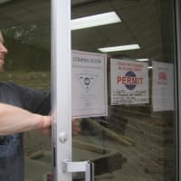 <p>Somers resident and karate teacher Richard Norbutt places a flyer on the new karate/yoga studio opening in Somers this month. </p>