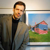 <p>Robert Carley, of Darien, poses with a photograph in his new exhibit, Flags Across America, at the Bruce Museum in Greenwich, Conn.</p>