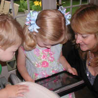 <p>The Taylor children work on an iPad with Laurie Allan, social worker at the STAR Rubino Family Center.</p>