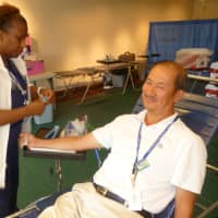 <p>New York Blood Center phlebotomist Karlean Darby takes  blood from Poo Phopitue at the Hastings Library.</p>