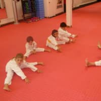 <p>Student/mentor Julian Raderman puts younger students through stretching exercises.</p>