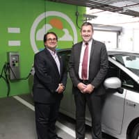 <p>Mike McGee of Darien, right, and Brian Heelan, Senior Vice President and Director of Operations for Ashforths management stand next to an electric car charging station in Stamford.</p>