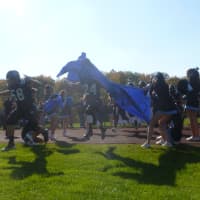 <p>The Rye Neck football team rushes through the team banner.</p>