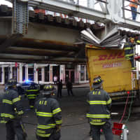 <p>Norwalk firefighters inspect the DHL box truck stuck under a train bridge at Washington Street on Friday afternoon. </p>