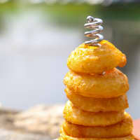 <p>The onion rings, cut from Spanish onions, are fried golden and served on a stacker. 
</p>