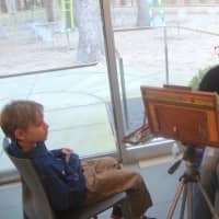 <p>Artist Jessica Miller paints a portrait of a young visitor using acrylic paint.</p>