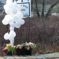 <p>Balloons and flowers honor the fallen students and educators at the sign for Sandy Hook School. </p>