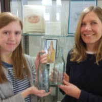 <p>Madeline Kearin and Laurie Kimsal hold bottles that bear the words, Mt. Kisco. </p>