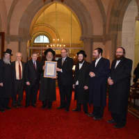 <p>Rabbi Shmuel David Weissmanl holds a framed
resolution honoring his father, Rabbi Michael Wessmandl.</p>