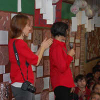<p>Artist in Residence Allison Marra (center), who created the idea of creating The Great Wall and painting lanterns, applauds the Hillside students.</p>