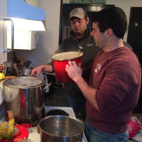 <p>John Wagner and Dan Latham begin the brewing process, straining and adding water to the oats after they have cooked. </p>