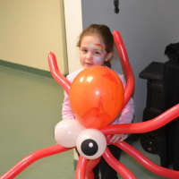 <p>A child gets her face painted and hugs her new spider balloon.</p>