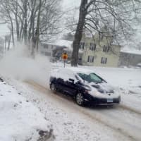 <p>A car burns some rubber and kicks up some snow as it spins its wheels going up a steep hill in Danbury. </p>