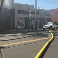 <p>Fire hoses stretch across the Post Road in Fairfield. </p>