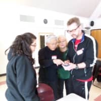 <p>Student Melissa Gross, adults Ifay Chang, Rebecca DeMartino and parent volunteer Christian Weinshenk figure out the iPhone at Technology Day.</p>
