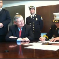 <p>Turn of River Volunteer Fire Department Chief Frank Jacobellis signs an agreement Wednesday consolidating services with the Stamford Fire Department as Mayor David Martin, sitting, looks on.</p>
